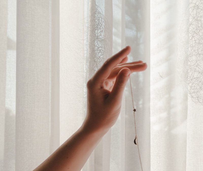 person holding window curtain during daytime